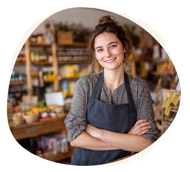 Young woman standing inside a small shop with arms crossed and smiling