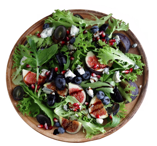 Fresh mixed green salad with figs, blueberries, olives, feta cheese, and pomegranate seeds in a wooden bowl